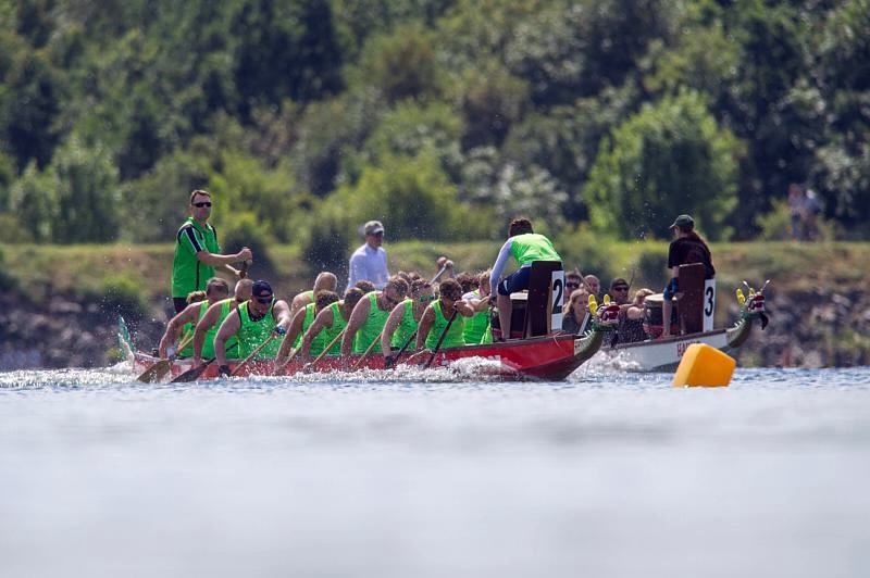 Dieses Bild zeigt 2 Teams in Drachenbooten, die gegeneinander um den Platz kämpfen.