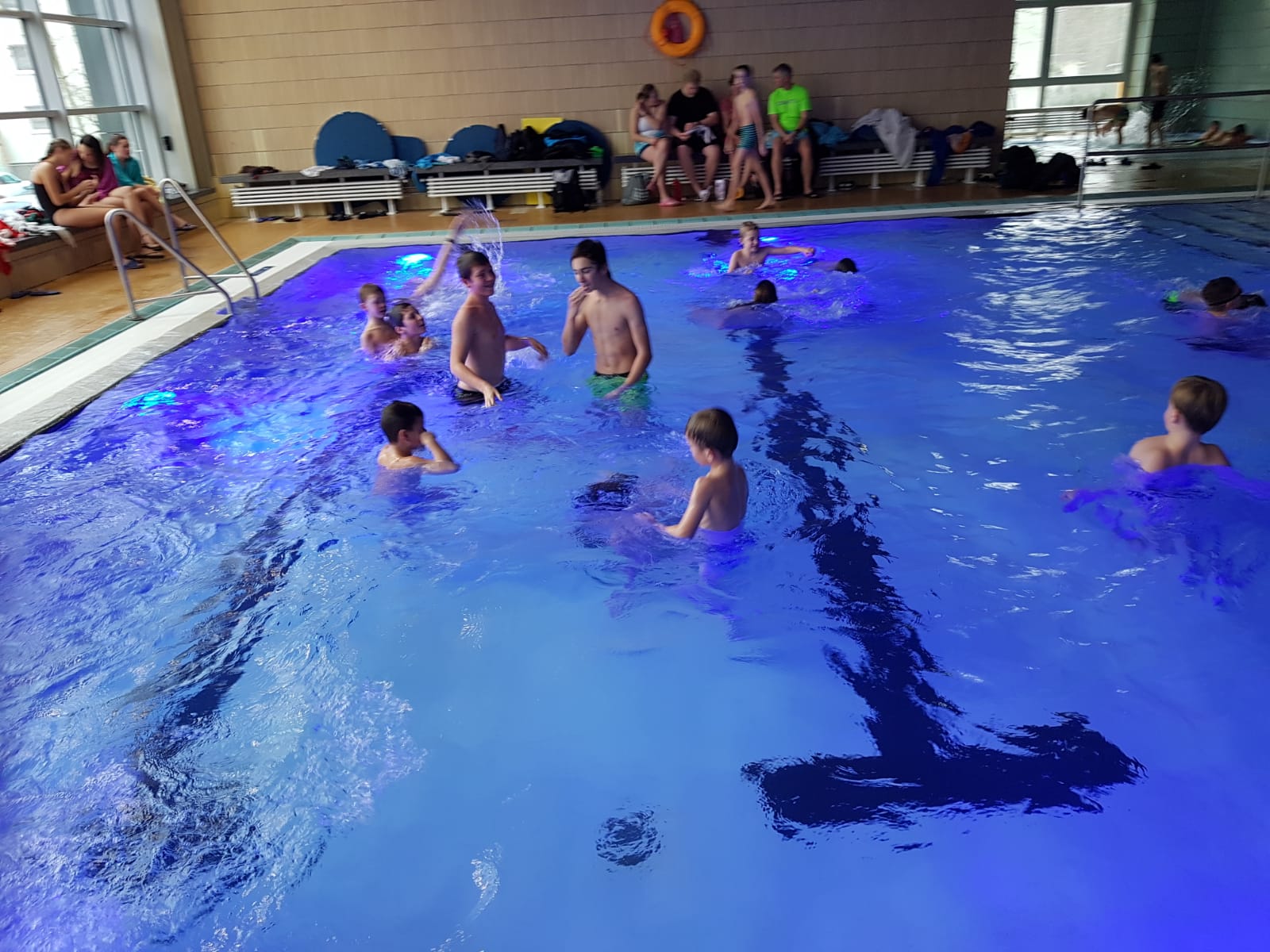 Ein Bild von mehreren Kindern und Erwachsenen, in einem Wasserbecken.