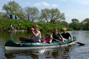 Das Bild zeigt 4 Personen in einem grünen Canadier.